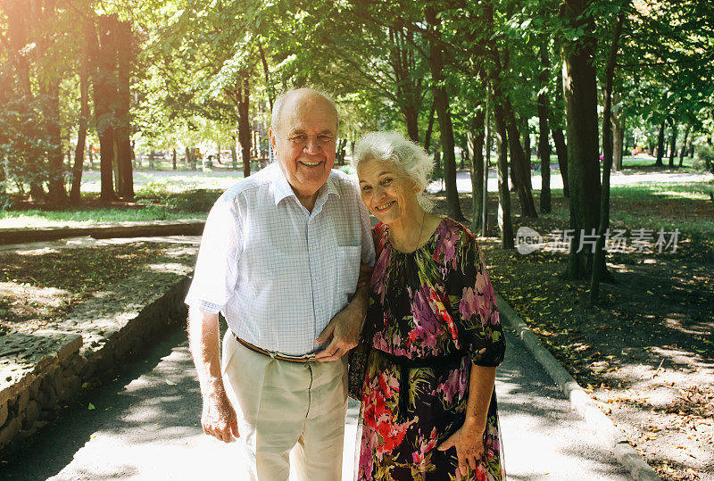 漂亮的老夫妇正在公园里散步。奶奶和爷爷在户外拥抱。金婚纪念日快乐。奶奶和爷爷的浪漫照片。真正的爱。