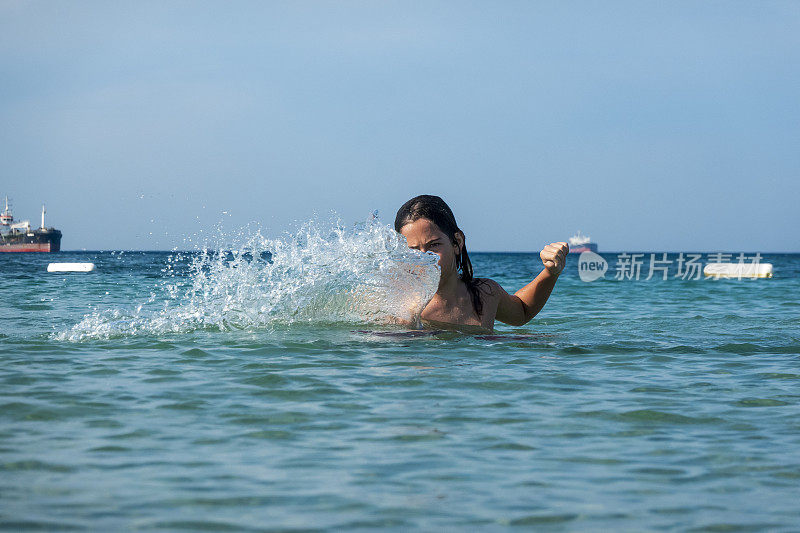 他用手在海里泼水。一个夏天的早晨。忒涅多斯岛。爱琴海北部，12岁的帅哥。长头发的