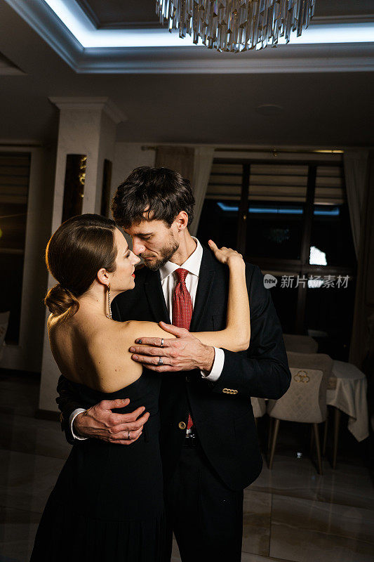 一个时髦的男人和一个穿着晚礼服的女人，一套西装和一条裙子，在一家豪华酒店的背景下摆姿势。
