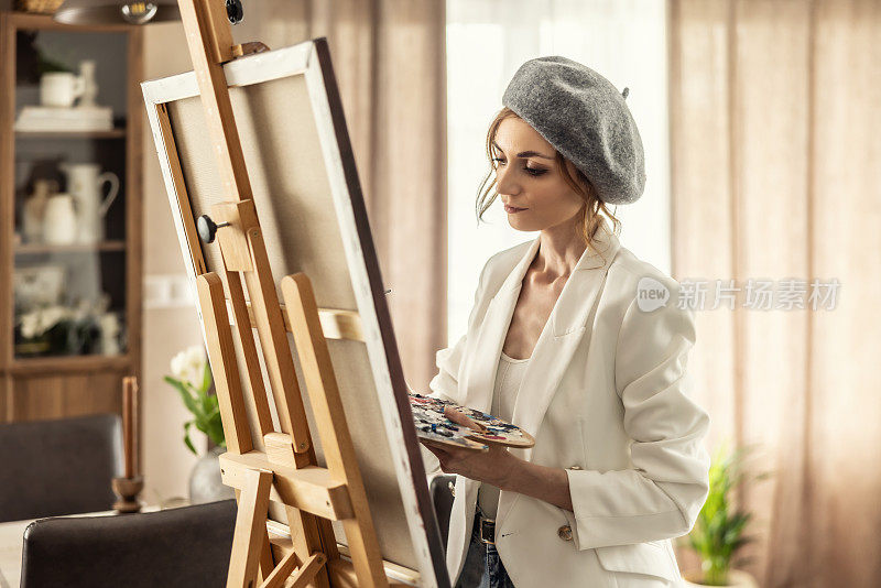 美丽的女画家在家庭美术工作室边画画边享受。女艺术家在艺术工作室从事抽象丙烯绘画。