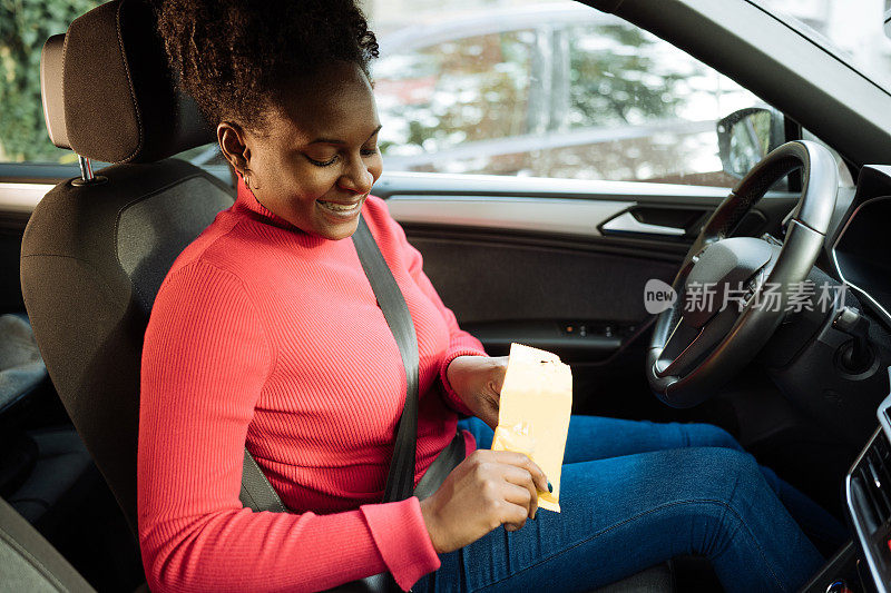 非裔加勒比妇女边开车边吃零食