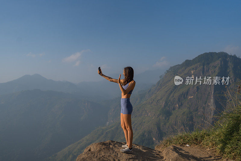 山顶上的年轻女子使用手机