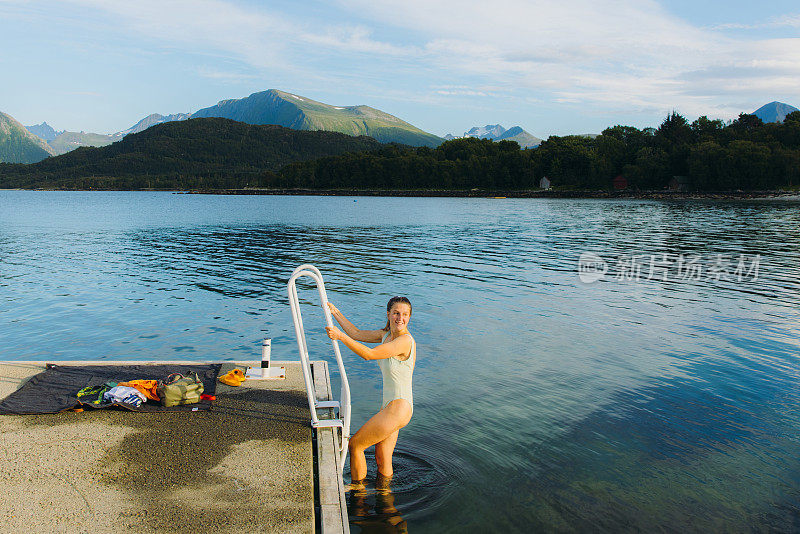 一个快乐的女人在挪威的山景海景中游泳