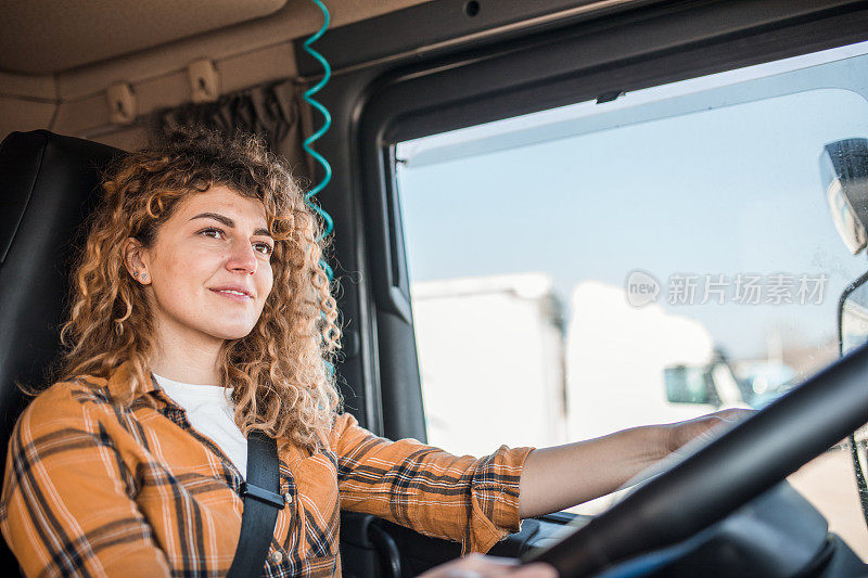 女卡车司机驾驶着卡车行驶在一个很长的运输路线上