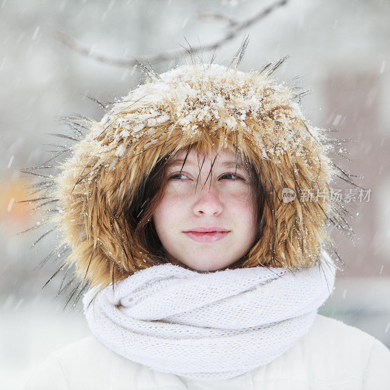 雪下穿着白色夹克的漂亮少女