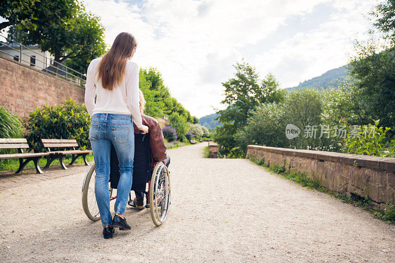 一对坐轮椅的年轻夫妇在公园里散步