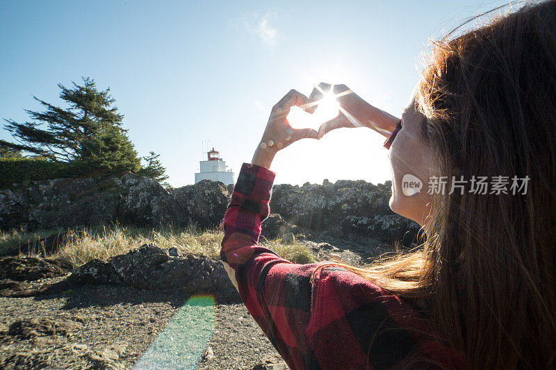 悬崖上的年轻女子做了心形手指架