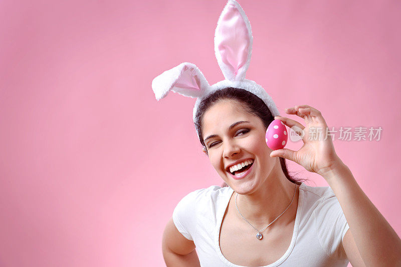 快乐的年轻女子戴着兔子耳朵拿着复活节彩蛋