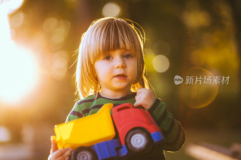 一个小男孩在公园里拿着卡车玩具
