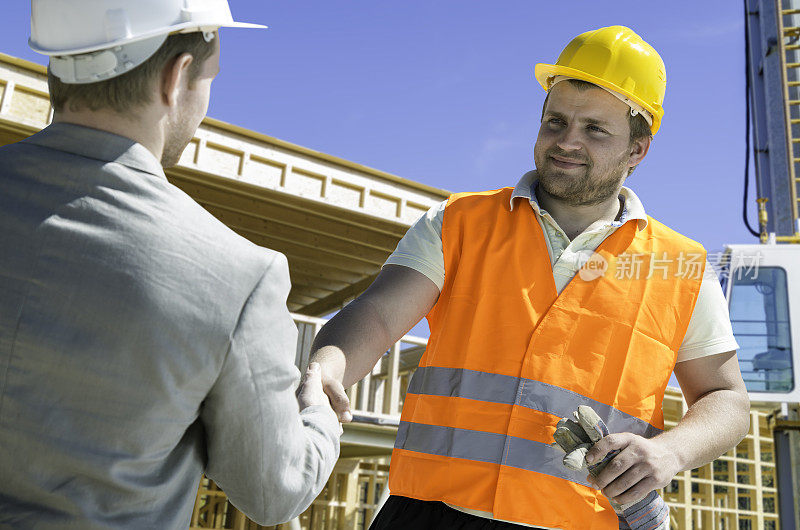 建筑师和建筑工人握手。