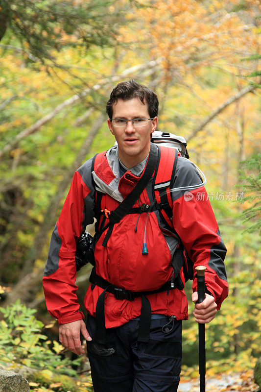 徒步旅行者背着背包在秋天的森林里行走