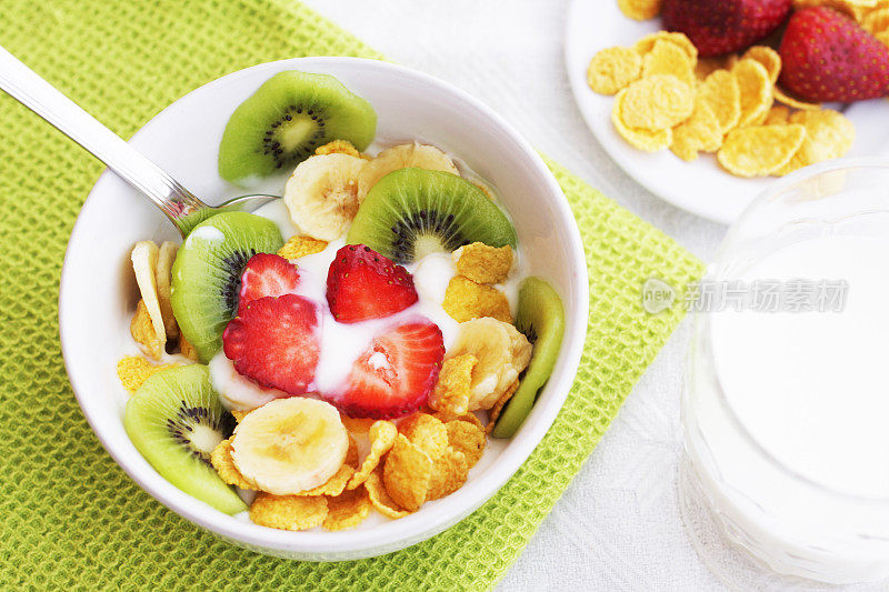 水果，麦片和酸奶放在白色的碗和牛奶玻璃