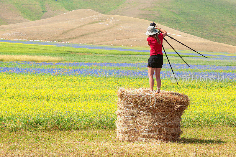 摄影师戴着帽子，穿着红衫，站在贝尔，Castelluccio，意大利