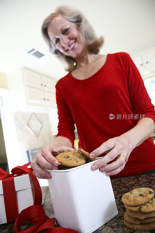 快乐女士穿红色把饼干放在礼品盒里