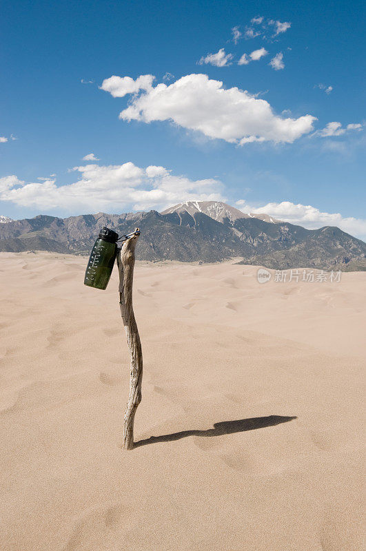 沙漠中干燥手杖上的水瓶