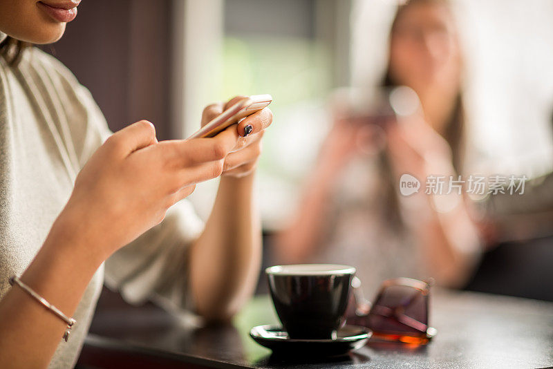 一个拿着手机的女人的手在咖啡店里