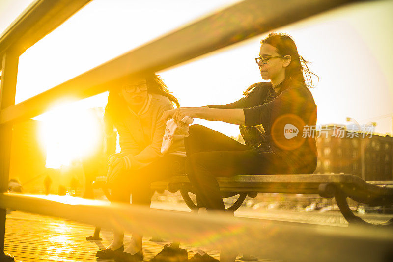 两个十岁的女孩坐在科尼岛人行道的长椅上