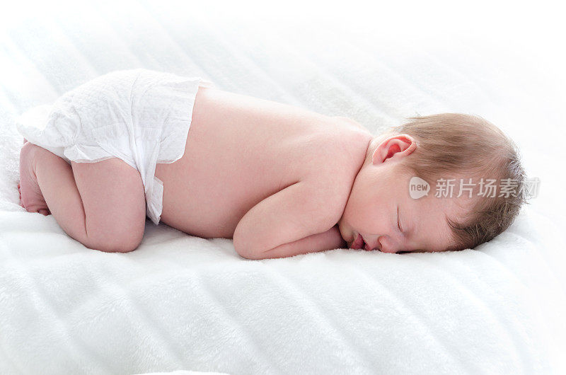 新生儿穿着尿布趴着睡觉。