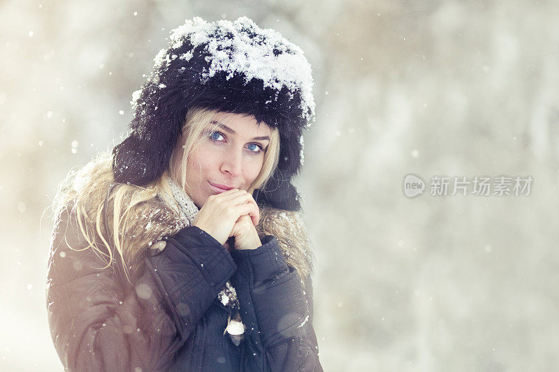 一个年轻的女人在一个冬天下雪的日子在户外