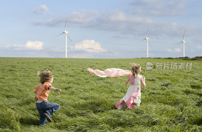 风力涡轮机在田地里，孩子们在前面奔跑