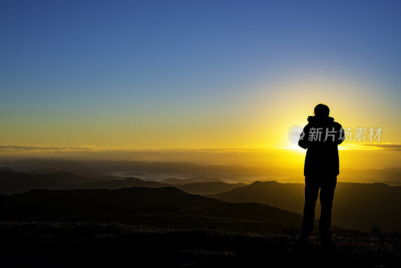 摄影师的剪影记录了山上的日出