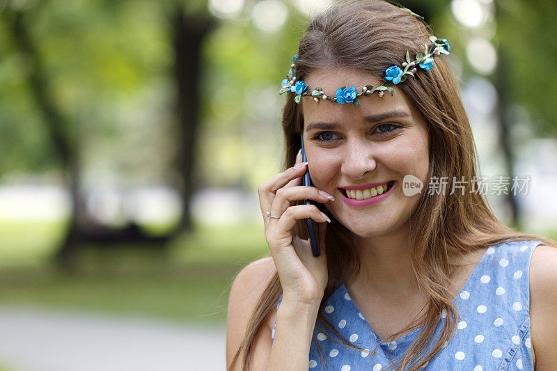 一个迷人的年轻女子正在公园里和手机聊天