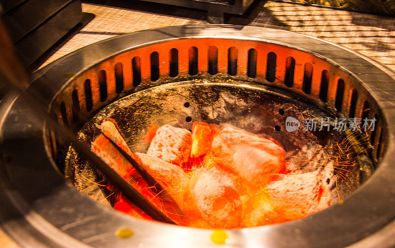 搅拌发光和燃烧传统的热天然木炭团在烧烤烤炉，跳舞的火火花动态模糊。