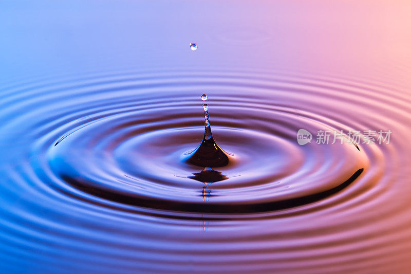 水滴近距离与同心涟漪在五颜六色的蓝色和琥珀表面