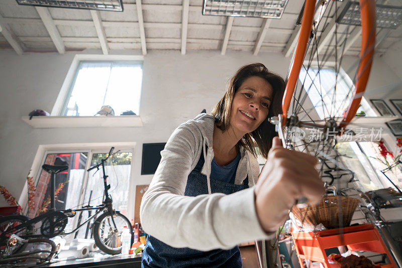 用工具调整自行车前轮的快乐的成年妇女