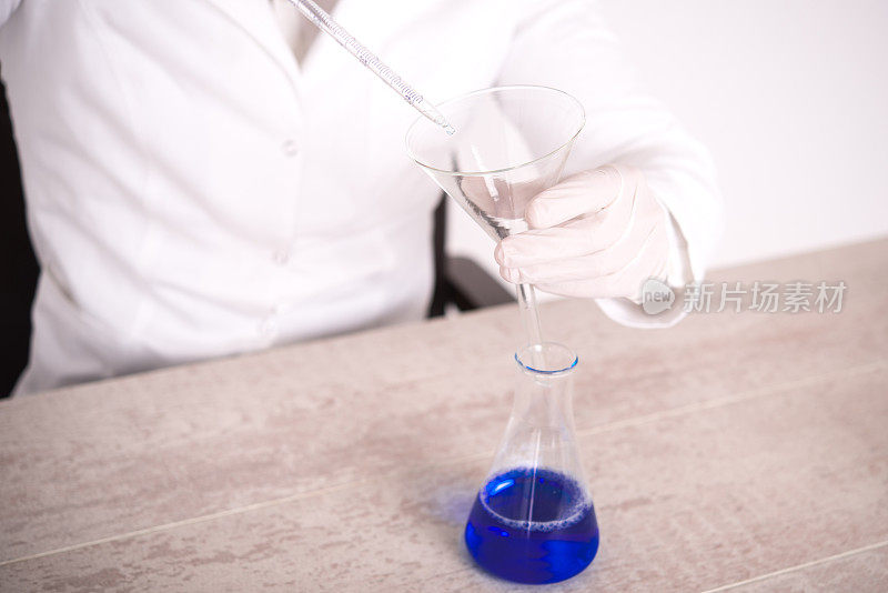 一个科学家举着一个长移液管在锥形烧瓶上的特写镜头