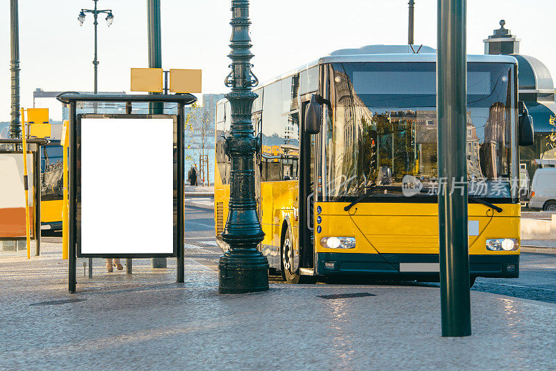 黄色的公共汽车和带有广告牌的公共汽车站