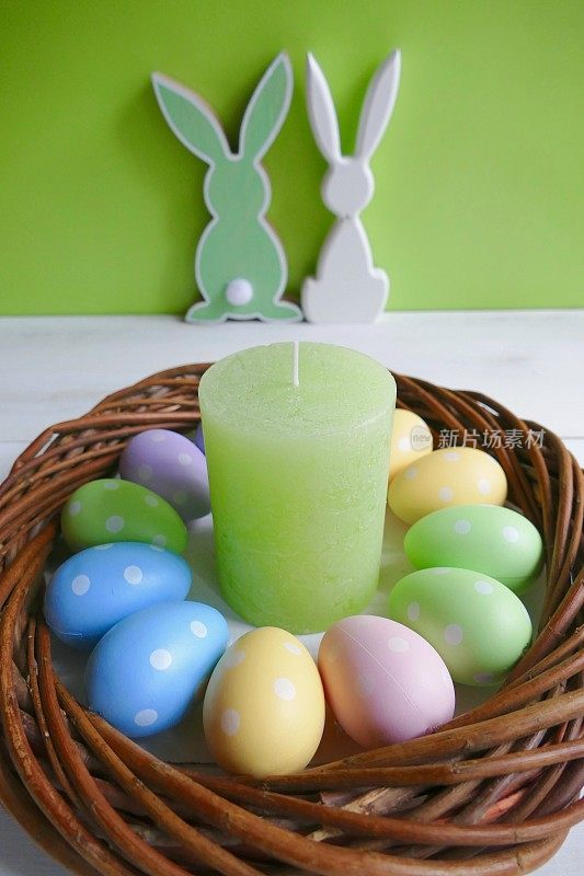 多色复活节花环与复活节兔子夫妇和绿色蜡烛