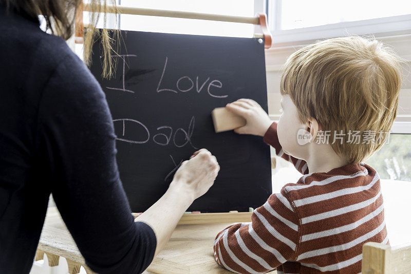 妈妈和小男孩在黑板上给爸爸写爱的留言