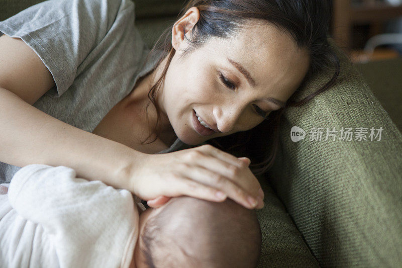 一个婴儿和一个有扶手枕的妈妈一起睡觉。