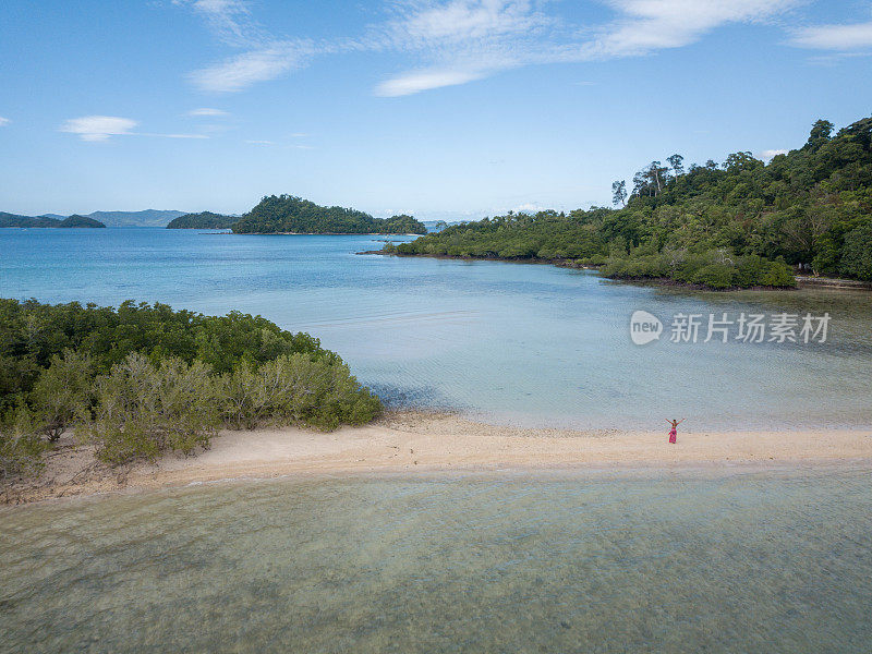 在菲律宾群岛，一名年轻女子在热带海滩上放松双臂，伸开双臂享受自由。人们旅行豪华度假目的地的概念