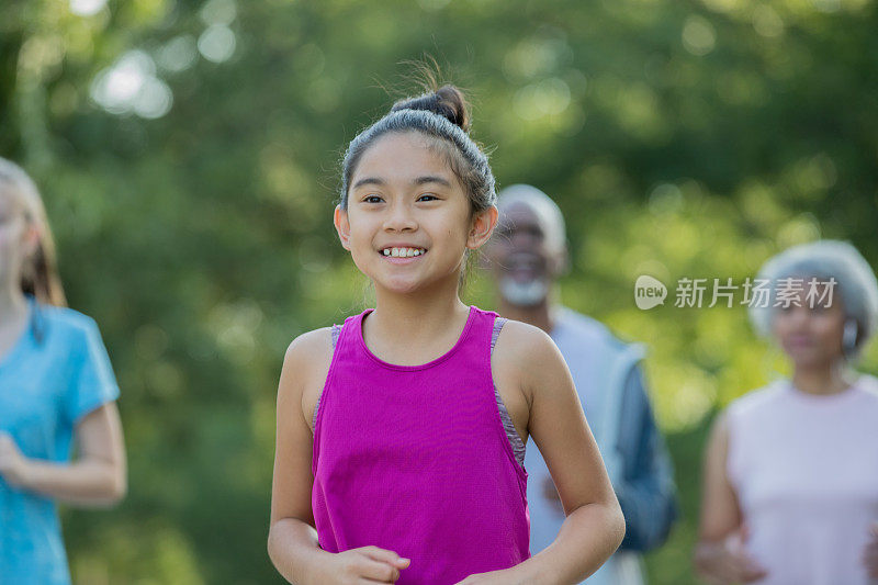 小学年龄的亚洲女孩在公园里跑步