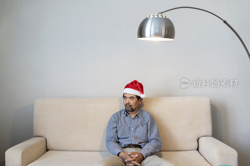 戴着圣诞帽的男人，坐在沙发上