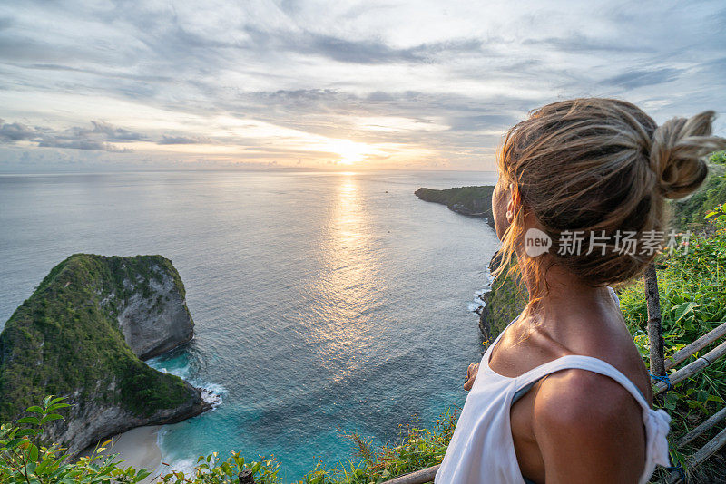 年轻女子俯瞰克林金海滩——蓝色和绿色的沙子，美丽的山在海上形成。旅游目的地度假，人们好奇的概念自然风景