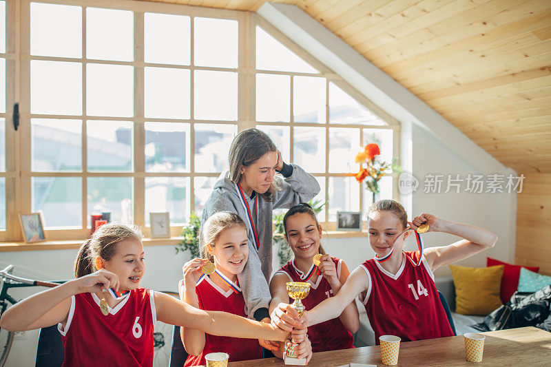 女子篮球运动员和女教练在家庆祝奖杯