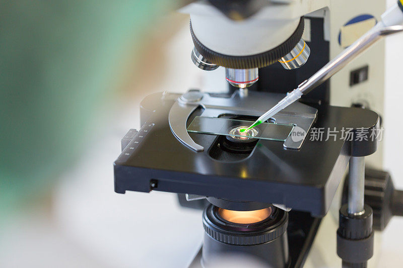 科学家在显微镜下将化学液体滴在载玻片上，概念科学与技术
