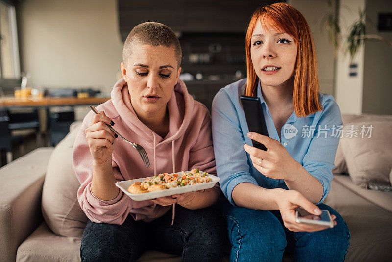 年轻女人边吃午饭边看电视