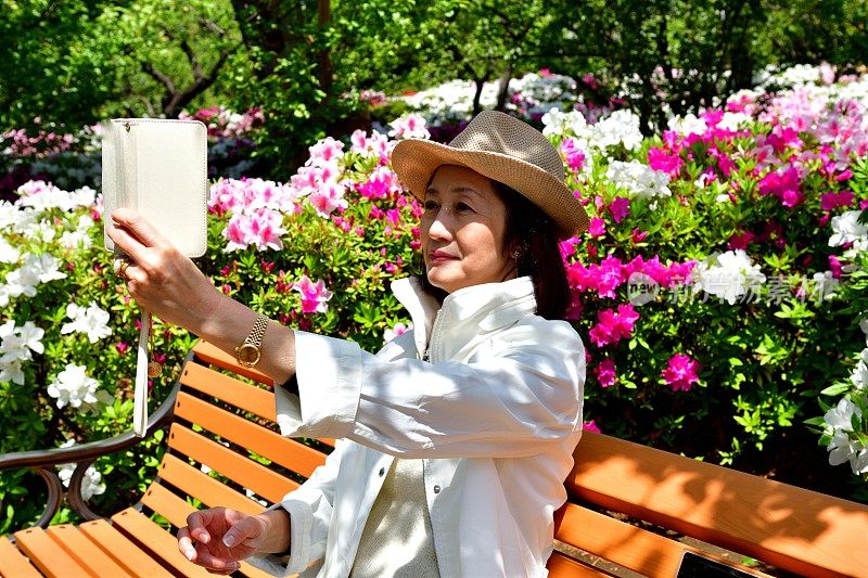 一名日本女子在公园里与盛开的杜鹃花自拍