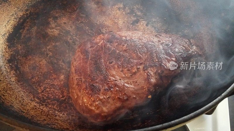 新鲜生牛臀牛排在平底锅中高温烧烤，烟熏