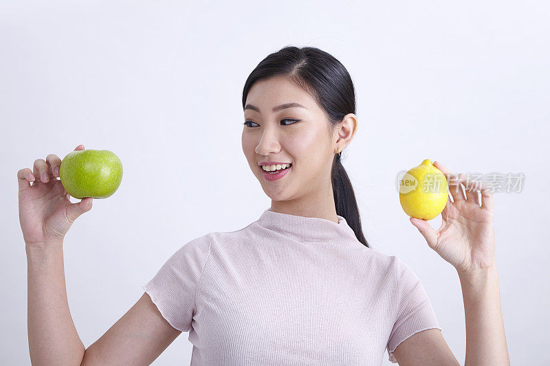 特写的中国民族妇女比较苹果和柠檬