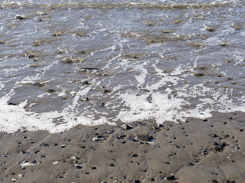 俄勒冈海滩上的湿沙岩石海浪泡沫