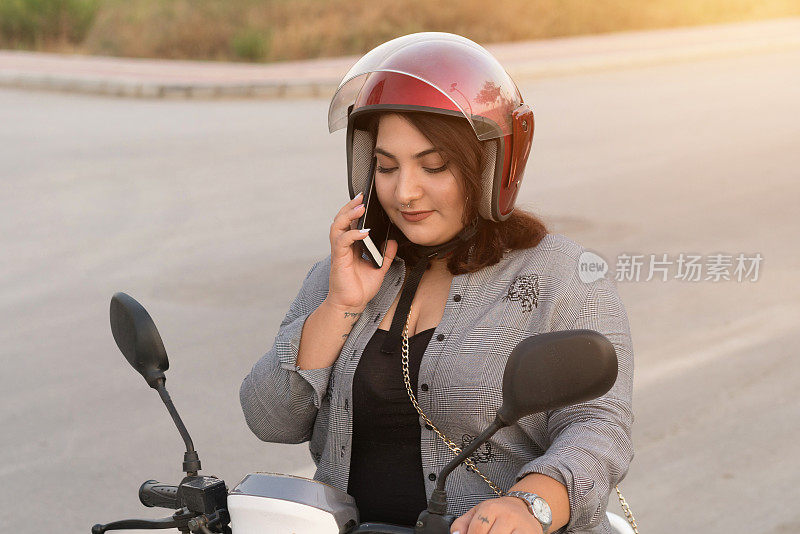 年轻女子在摩托车上打电话