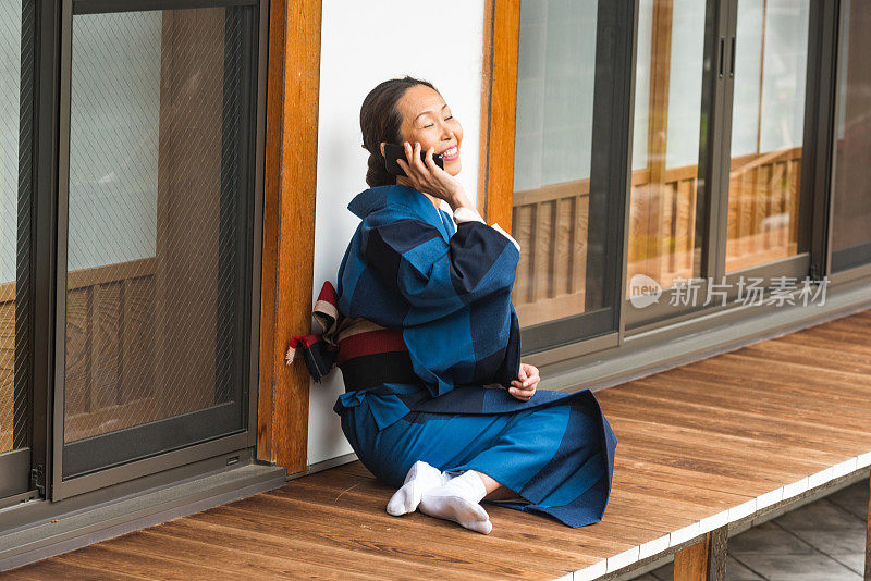 成熟的日本妇女穿着传统和服在京都寺外打电话