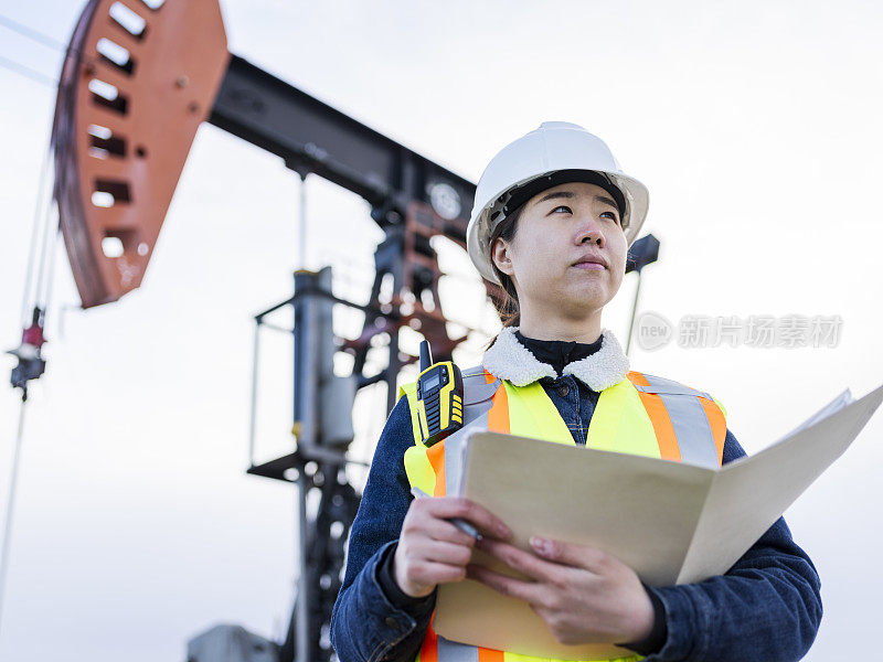 女石油工人在油田与文件夹