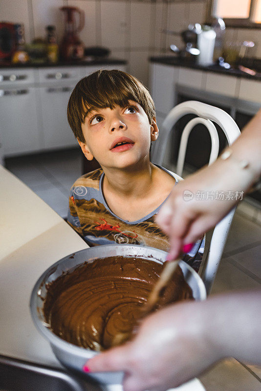 男孩看着妈妈做巧克力蛋糕