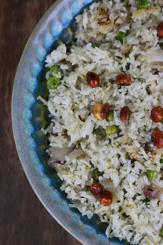 这是用印度香米、孜然籽、洋葱、豌豆和烤花生做成的炒饭，放在陶瓷蓝色盘子里，这是印度德里的印度菜